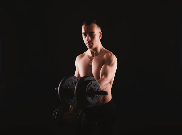 Photo of young man working at his biceps with dumbbells — 图库照片