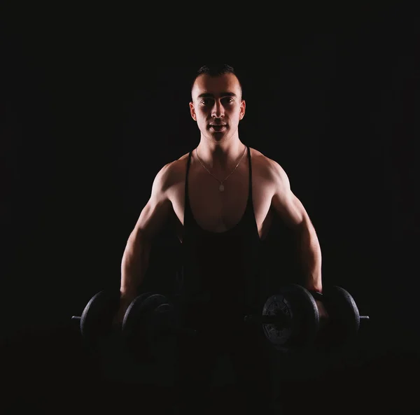 Photo of happy fitness man working with dumbbells over dark back — 스톡 사진