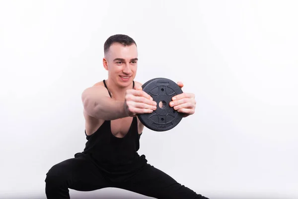 Fitness-junger Mann hantiert mit Gewichten über weiße Wand — Stockfoto