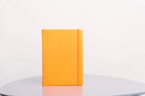 Livro laranja, agenda ou planejador em pé sobre uma superfície cinza e fundo branco. Modelo de livro . — Fotografia de Stock