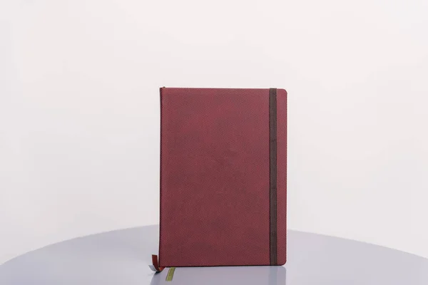 Brązowa książka, program lub planista stojący na szarej powierzchni i białym tle. Wzór książki. — Zdjęcie stockowe