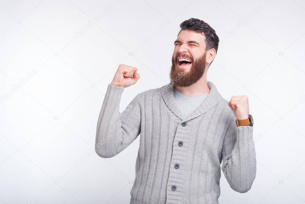 Photo of happy man celebrating success while standing over white