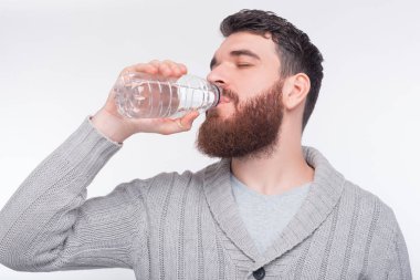 Hidrate olarak kal. Genç adam plastik şişeden su içiyor..