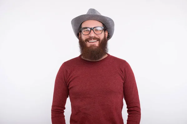 Um retrato de um belo jovem barbudo com óculos e um chapéu perto de um fundo branco . — Fotografia de Stock