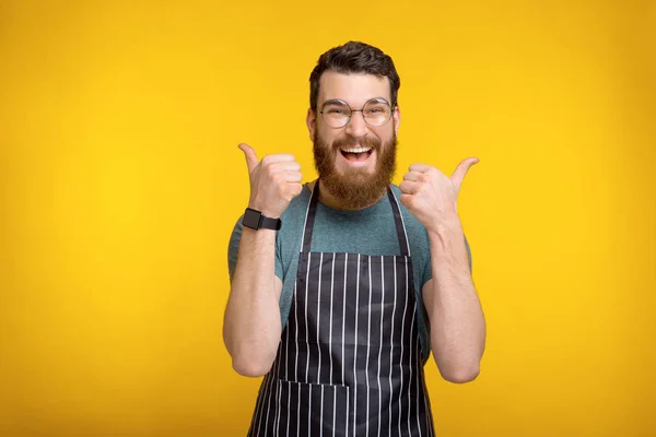 Фото веселого улыбающегося молодого шеф-повара в форме, показывающего большой палец вверх. — стоковое фото