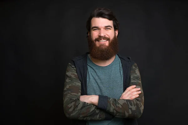 Confident handsome bearded man is crossing his arms on black background. — 스톡 사진