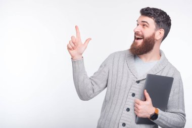 Adam beyaz arka planda yukarı bakıyor ve dizüstü bilgisayarını tutuyor..
