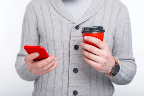 Hablemos y tomemos un café. El hombre sonriente está teniendo una conversación en su teléfono y sosteniendo una taza roja para ir . —  Fotos de Stock