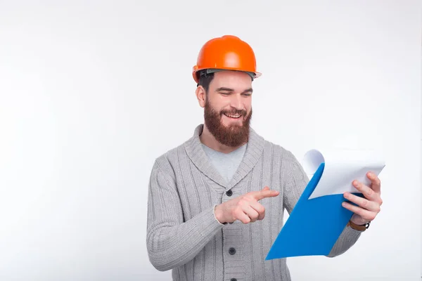 Young constructor man is checking his list. He wears an orange hard protection hat. — Stock Photo, Image