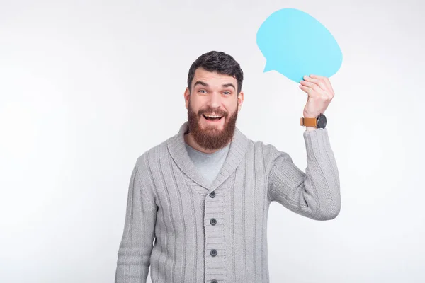 Überraschter junger bärtiger Mann hält eine hellblaue Blase über seinem Kopf. — Stockfoto