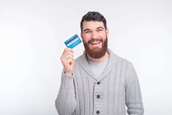 Deberías tener una de estas geniales tarjetas de crédito. Hombre barbudo excitado sostiene una tarjeta de crédito sobre fondo blanco . — Foto de Stock