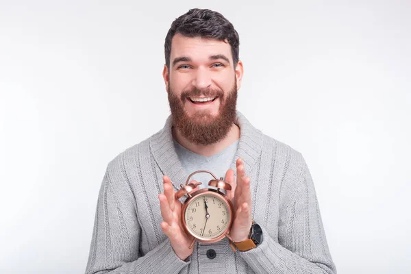 Ας εκτιμήσουμε το χρόνο. Χαρούμενος άνθρωπος κρατά ένα ξυπνητήρι σε λευκό φόντο. — Φωτογραφία Αρχείου