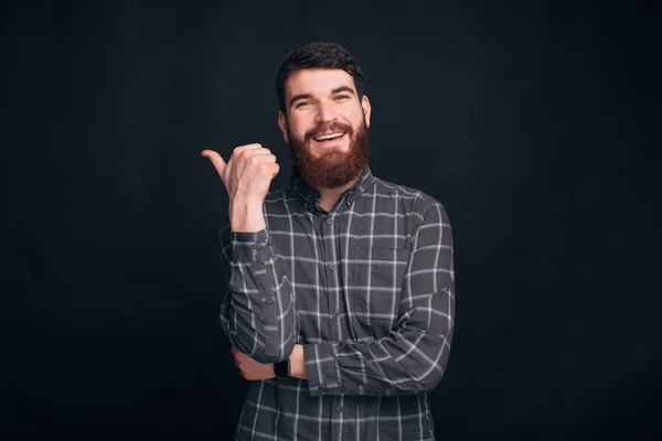 Olha para a direita, há espaço para a tua mensagem. O homem está apontando para o fundo ao lado dele . — Fotografia de Stock