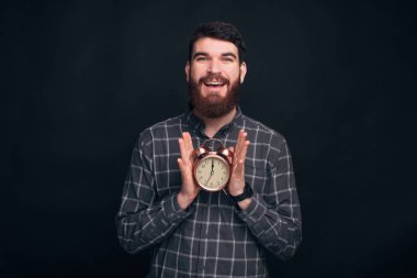 Vakit geldi. Neşeli genç adam elinde bir çalar saat tutuyor, kameraya gülümsüyor..