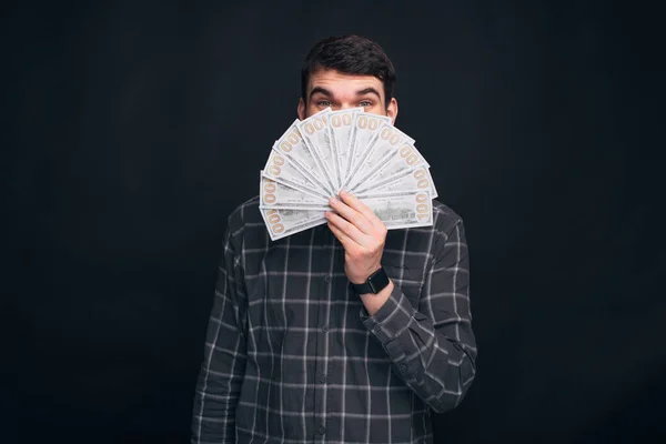 Young man is covering his face to eyes with a bunch of money. — Stock Photo, Image