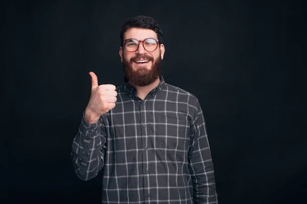 Fiatal szakállas férfi szemüveges mutatja, mint vagy hüvelykujj fel gesztus. — Stock Fotó