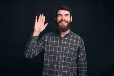 Gülümseyen adam karanlık duvarın üzerinde dururken selam veriyor.