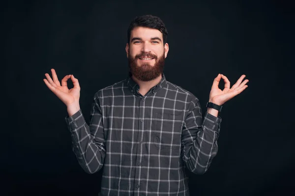 Lächelnder Mann versucht Zen auf schwarzem Hintergrund zu erreichen. — Stockfoto