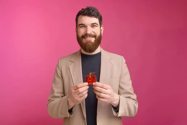Портрет усміхненого чоловіка в костюмі, що тримає маленький червоний подарунок — стокове фото