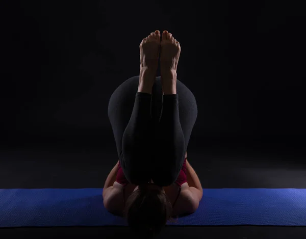 Молода приваблива спортивна жінка практикує йогу, на чорному тлі . — стокове фото