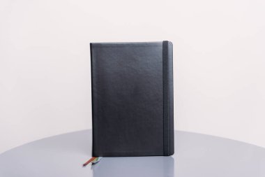Kara kaplı defter, gündem ya da planlamacı gri bir zemin ve beyaz bir zemin üzerinde duruyor. Kitap şablonu.