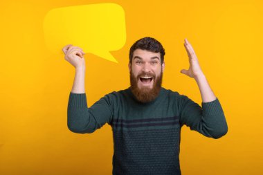 Amazed handsome man with beard holding yellow speech bubble