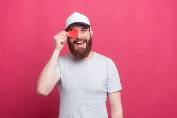 Fröhlicher schöner Mann mit rotem Papierherz über den Augen — Stockfoto