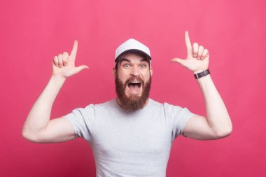 Amazed cheerful bearded man pointing up at product