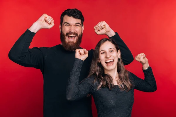 Foto de pareja celebrando el éxito sobre fondo rojo —  Fotos de Stock