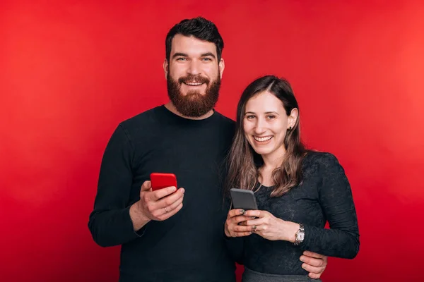 Foto de casal feliz segurando smartphones e olhando para a câmera — Fotografia de Stock