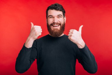Kızıl Torba 'da parmaklarını gösteren neşeli sakallı bir adamın fotoğrafı.
