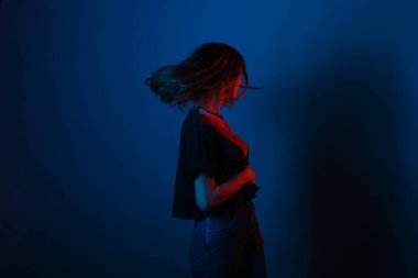 Young girl shaking with her hair on blue background lighted with