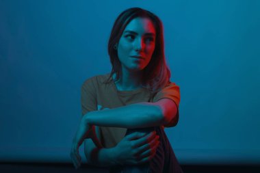Gorgeous young woman is looking aside, at a red light, on light 