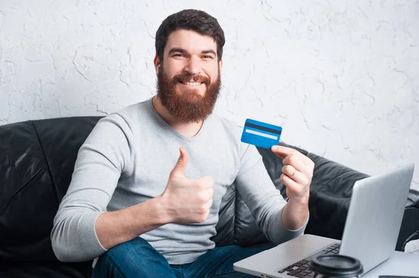 Sonriente barbudo mostrando pulgares hacia arriba y tarjeta de crédito — Foto de Stock