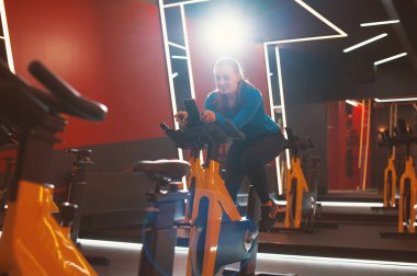 Spor salonunda bisiklet egzersizi yapan bir kadın.