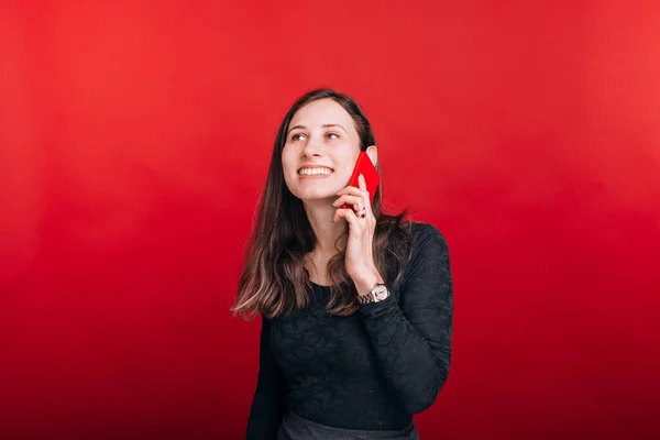 Mosolygós lány beszél a telefonon a piros háttér — Stock Fotó