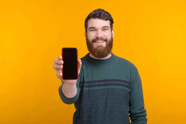 Veja esta oferta online ou anúncio. Bonito homem está mostrando sua tela em branco do telefone no fundo amarelo — Fotografia de Stock