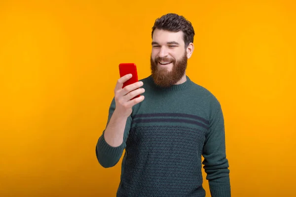 Happy young man is looking at the phone, video talking on yellow background — Stock Photo, Image