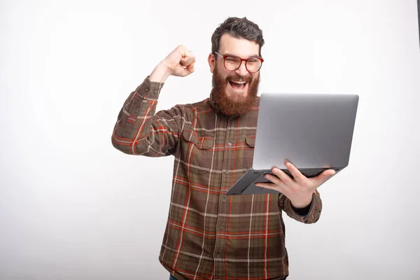 Jeune homme fait geste gagnant en regardant son ordinateur portable sur fond blanc — Photo