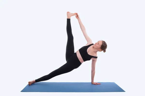 Jonge sport vrouw doet yoga op mat over witte achtergrond in studio — Stockfoto