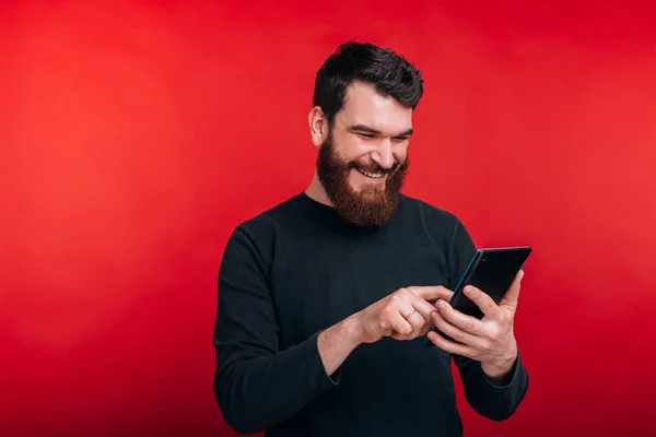 Homme heureux surfer sur Internet avec tablette debout sur fond rouge — Photo