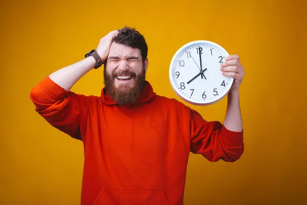 El tiempo es muy rápido. El barbudo con los ojos cerrados y la mano en la cabeza sostiene un reloj blanco . — Foto de Stock