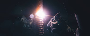 Kaynakçı çeliğiyle çalışan bir adam. Dışarıdaki elektrikli kaynak makinesini kullanıyor.