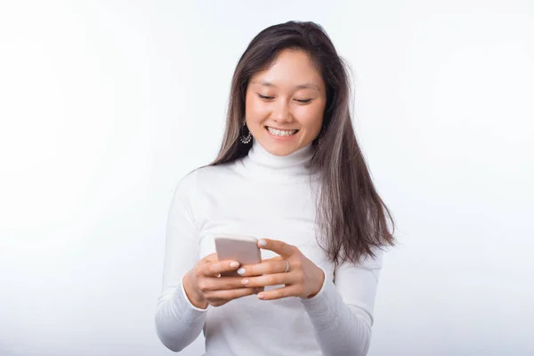 Mooie vrolijke vrouw staan over witte achtergrond en met behulp van smartphone — Stockfoto