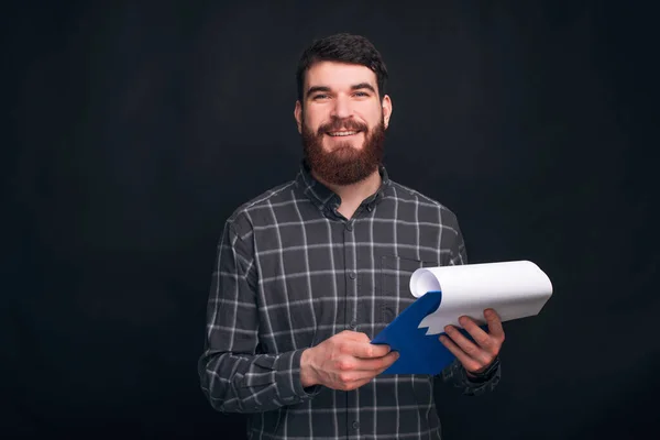 Jovem bonito segurando placa clipe e olhando confiante para a câmera — Fotografia de Stock