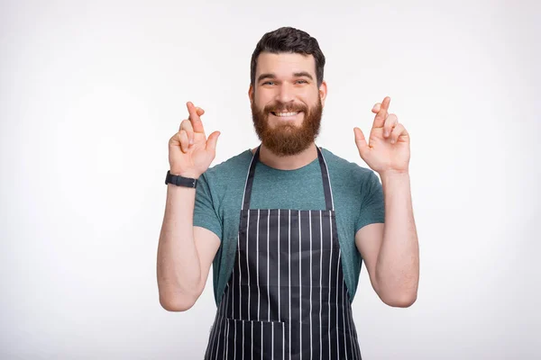 Очаровательный молодой шеф-повар скрещивает пальцы и мечтает — стоковое фото