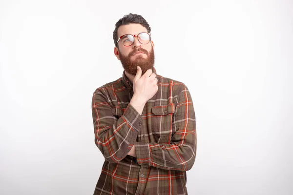 Jóképű, szakállas férfi szemüvegben és gondolkodik valamin. — Stock Fotó