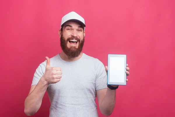 Hombre barbudo asombrado mostrando los pulgares hacia arriba gesto y la pantalla en blanco tableta — Foto de Stock