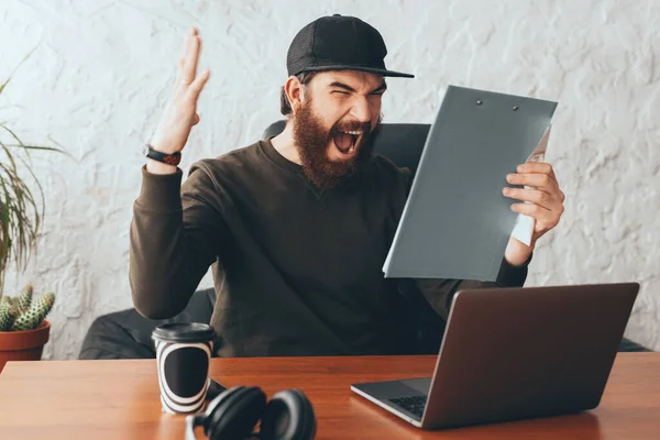 Angry bearded man screaming in office and looking at paper work — Stock Photo, Image