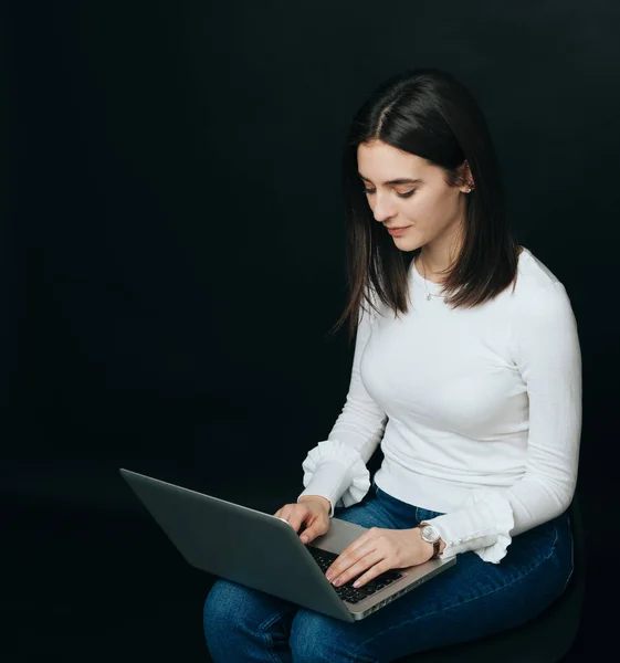 Giovane bella studentessa che lavora su computer portatile su sfondo scuro — Foto Stock